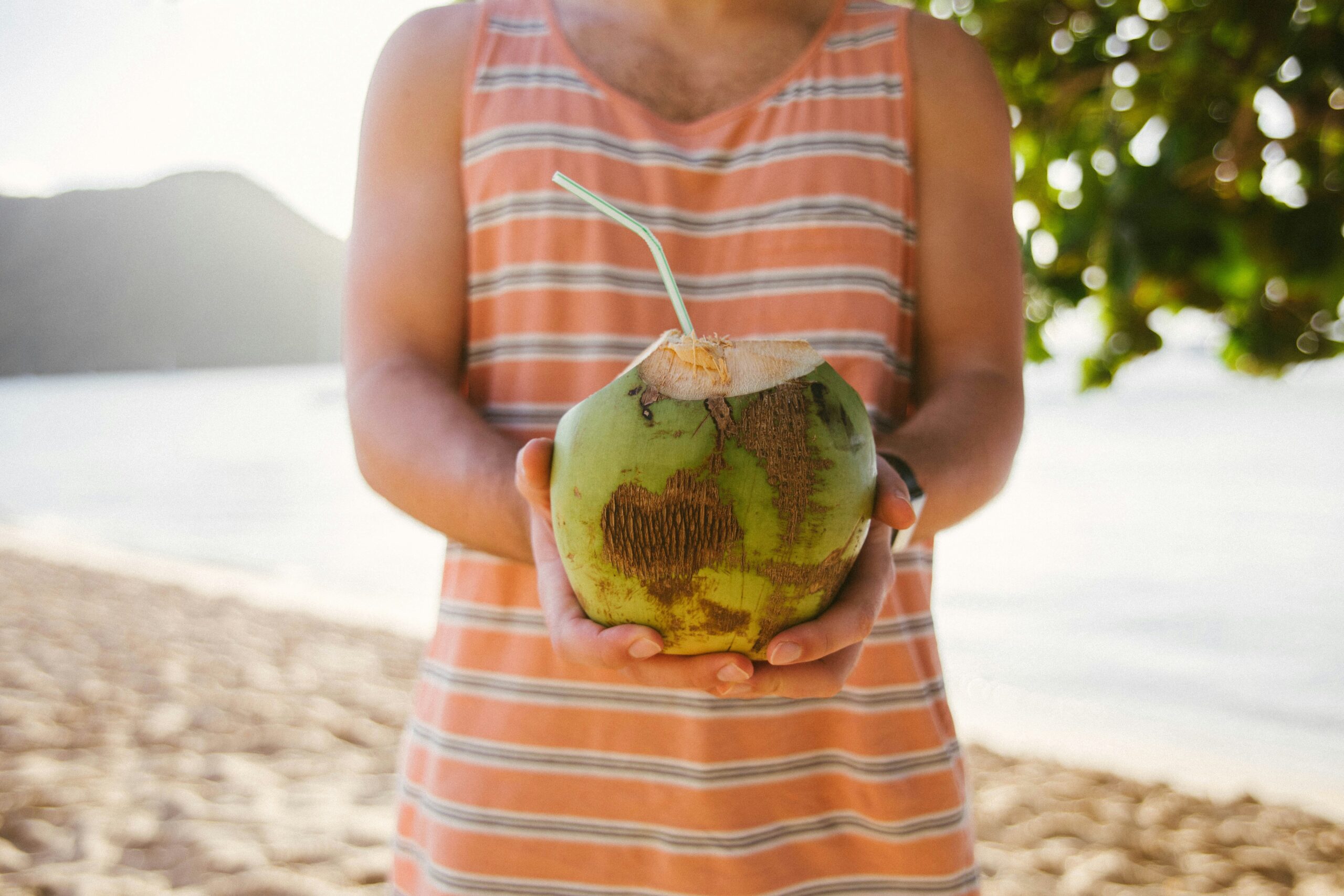 Smiling woman holding tropical fruit in front of palm trees, symbolizing successful baggage recovery