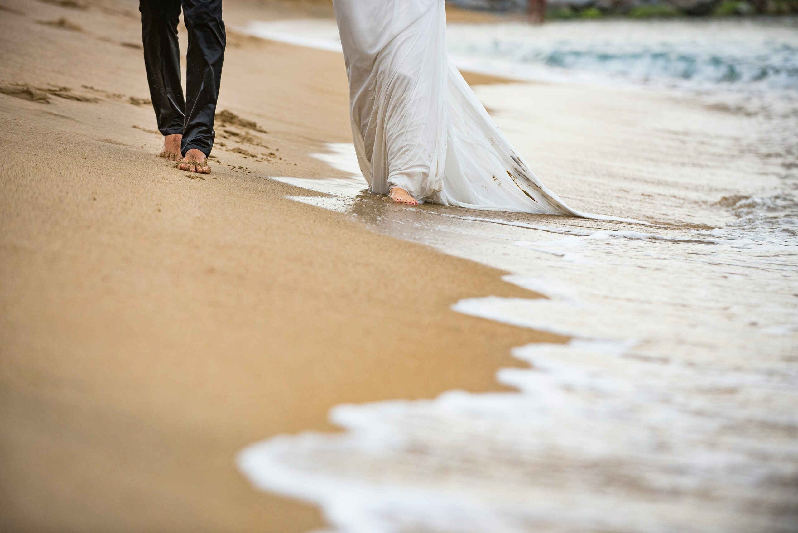 Photo of a bride holding her recovered wedding dress in front of a tropical beach